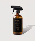 Amber glass spray bottle of Crew Love Home Surface Tonic luxury aromatic cleaner on a bright, minimal background.