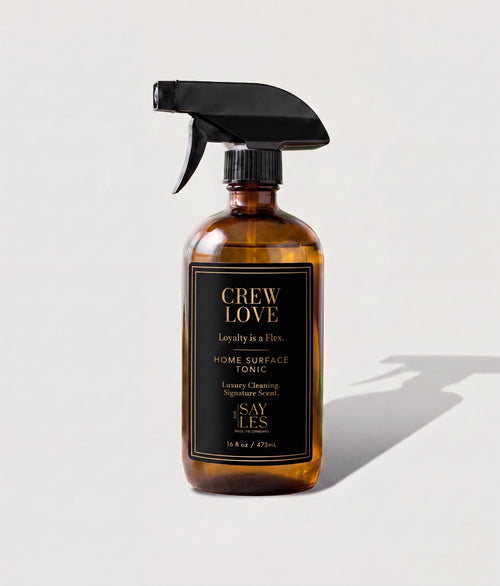 Amber glass spray bottle of Crew Love Home Surface Tonic luxury aromatic cleaner on a bright, minimal background.