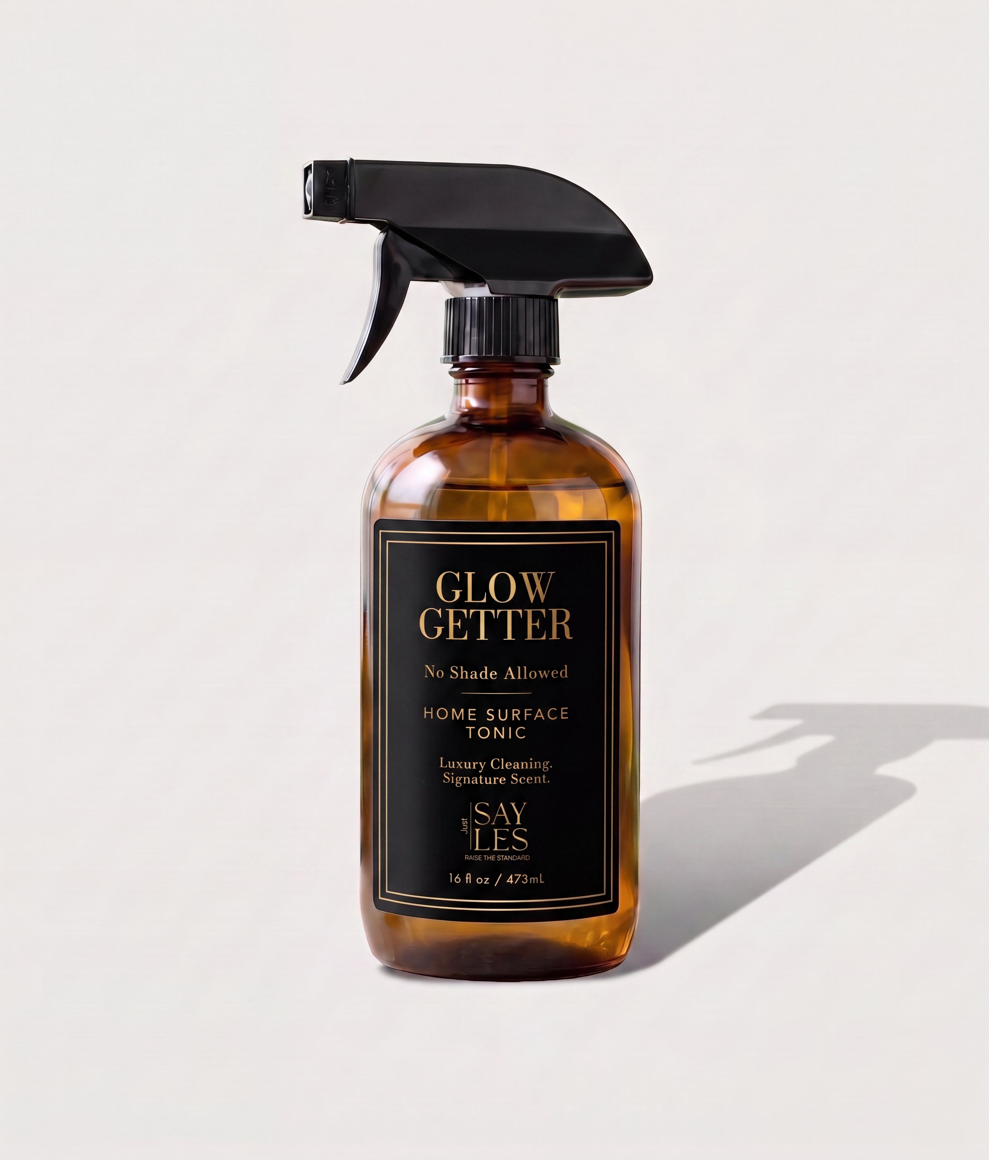 473ml amber glass spray bottle of Glow Getter Home Surface Tonic luxury cleaning spray on a minimal background.
