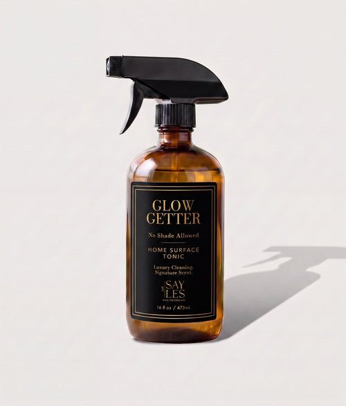 473ml amber glass spray bottle of Glow Getter Home Surface Tonic luxury cleaning spray on a minimal background.